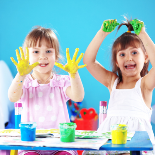 two little girls finger painting and showing their painted hands to the camera