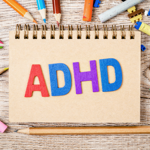 ADHD in colorful felt letters on a spiral notpad with colored pencils around